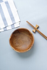 Mangkok kayu or empty wooden bowl and chopsticks on bamboo sushi roller and blue stripes napkin. Tableware, concept of table serving, top view