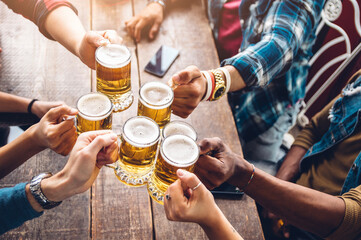 Group of people enjoying and toasting a beer in brewery pub - Friendship concept with young people...