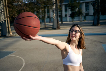 Girl holding a basketball looking at it with optimism thinking about her dream of an urban...