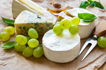 Various types of cheese, basil and grapes