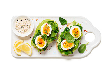 Healthy toast with sliced avocado, boiled eggs, spices and fresh spinach. Delicious breakfast or snack isolated on white background