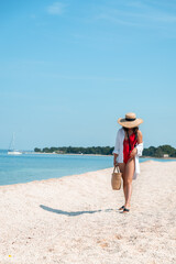 Fototapeta na wymiar young stunning woman in red swimsuit walking by sea beach