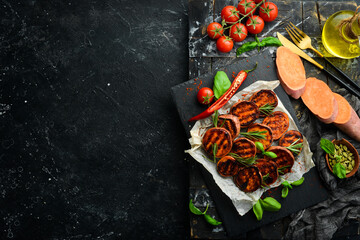 Fototapeta na wymiar Fried sweet potatoes with rosemary, paprika and chili peppers on a black stone plate. Top view. Free space for your text.