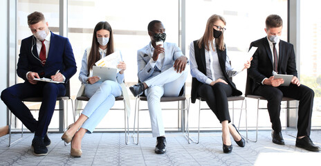 Stressful business people waiting for job interview with face mask, social distancing quarantine during COVID19 affect