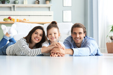Young Caucasian family with small daughter pose relax on floor in living room, smiling little girl...