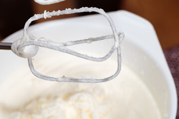 Whipped cream on a whisk of a mixer.