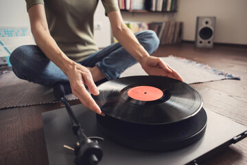 Young woman listening to music, relaxing, enjoying life at home. Girl wearing warm winter clothes having fun. Turntable playing vinyl LP record. Leisure, music, hobby, lockdown, lifestyle concept