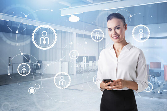 Attractive smiling young businesswoman holding smartphone and po