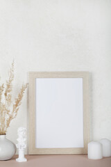 Portrait empty wooden frame mockup, dried pampas grass, small statue and candles on white background, interior, home design. Art concept. copy space. 