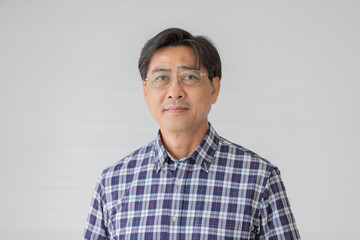 Portrait close up shot of middle aged asian male model with short black hair wearing blue plaid shirt with stand smiling in front of white background
