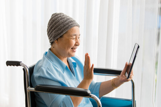 Older Asian Woman Patient Covered The Head With Clothes Effect From Chemo Treatment In Cancer Cure Process Waving Hand To Greeting Family Members