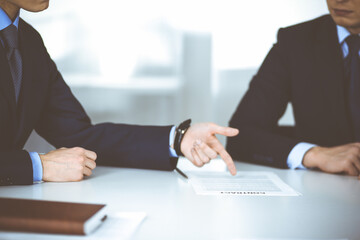 Business people discuss a contract, sitting at the desk in a modern office. Unknown businessman with a colleague, lawyers at negotiation. Teamwork and partnership concept