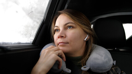 Fototapeta na wymiar Young beautiful woman listening music in headphones sitting in backseat in car. 3840x2160