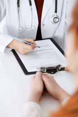 Unknown woman-doctor filling up an application form while consulting patient. Medicine concept