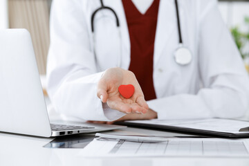 Unknown woman-doctor holding little heart in her hands. Children s cardiology and medical care,...