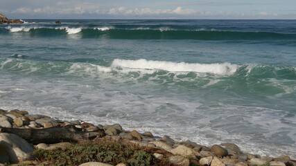 Ocean waves and rocks, Monterey, Northern California, USA. 17-mile drive near Big Sur, seaside golf tourist resort on Pacific Coast Highway. Splashing water and sea breeze of Pebble beach. Road trip.