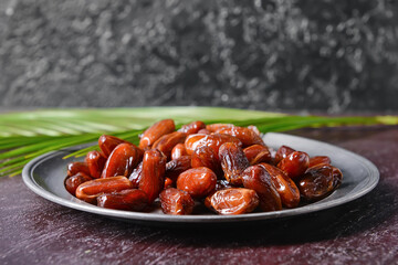 Plate with sweet dried dates on dark background