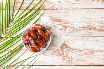 Bowl with sweet dried dates on light wooden background