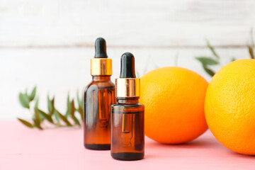 Bottles of orange essential oil on color table