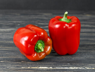 Two bell peppers on a dark wooden background.