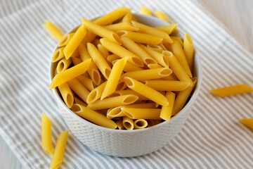 Uncooked Organic Penne Pasta in a Bowl, side view.