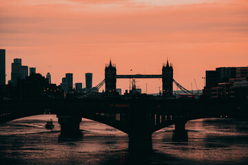 London UK February 2021 Late afternoon winter sunset over the river Thames, outline of the Tower Bridge in the background. Double decker buses crossing the bridge in the foreground