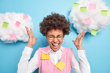 Busy curly Afro American office worker has many tasks at same time exclaims in panic raises hands...