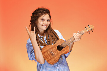 Portrait of funny young woman playing ukulele. Happiness and carefree concept