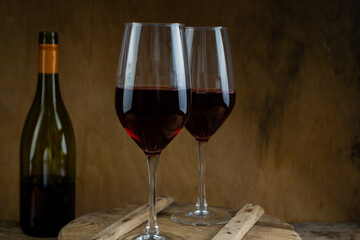 Two glasses of red wine. The bottle of wine is on the table. Wine background. Still life. Alcoholic drink in a glass. Wooden background
