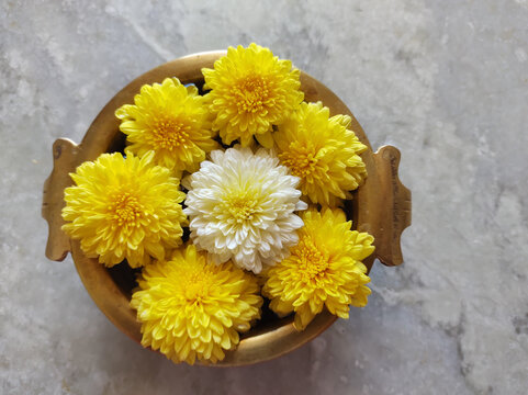 Overhead Shot Of Yellow Flowers In A Wooden Bowl On A Marble Table