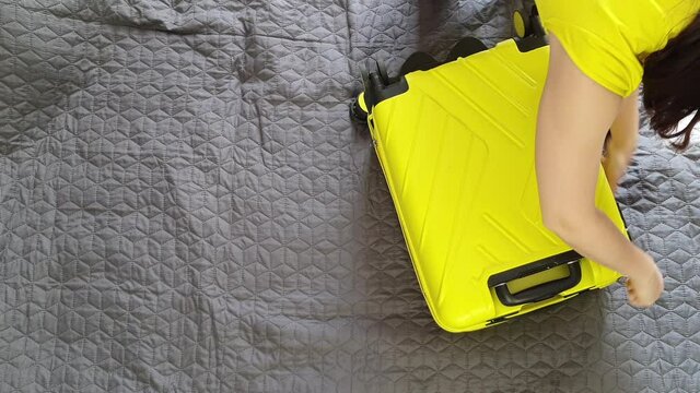 overhead view woman packing yellow valise