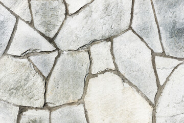 Mosaic stones construction backdrop. Grunge uneven brick wall pattern. Pieces of cracked blocks in concrete wall background. Gray concrete joint. Decorative exterior wall.
