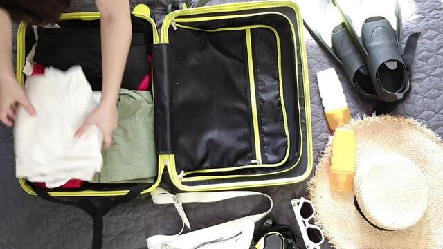 overhead view woman packing yellow valise
