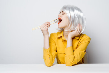 Obraz premium attractive woman in wig chopsticks sushi eating