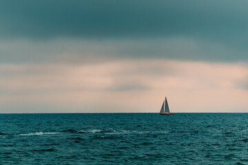 a lonely yacht goes to sea on a cloudy day. sailing on the water