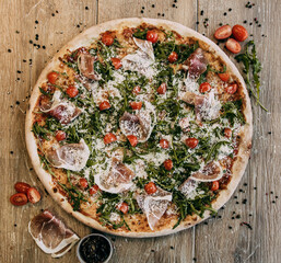 Pizza with bacon arugula and tomatoes. Top down view on delicious single round pizza with arugula lettuce and bacon meat toppings