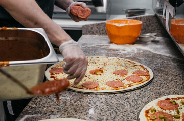 Scoop with tomato paste for greasing pizza. Chef starts to prepare pizza at a pizzeria