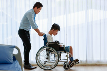 A doctor pushing the wheelchair of a disabled boy with care and a kindly gesture