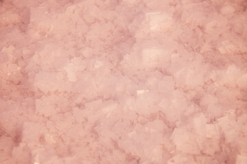 Blurry crystals of pink salt at the bottom of a salt lake with clear pink water. Blurred image in defocus. Background for salt producers