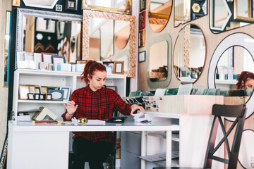 Woman shop assistant working in mirror and frames store