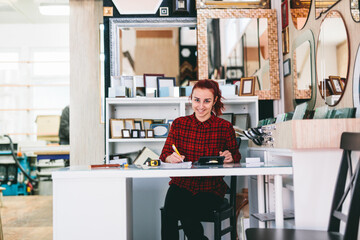 Woman shop assistant working in mirror and frames store