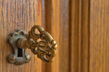 Stary klucz włożony do zamka dębowej szafy. - obrazy, fototapety, plakaty