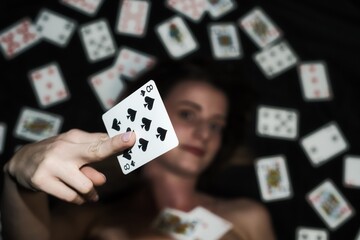 Fotografie einer jungen Frau welche eine Pik 8 Pokerkarte in die Kamera hält.