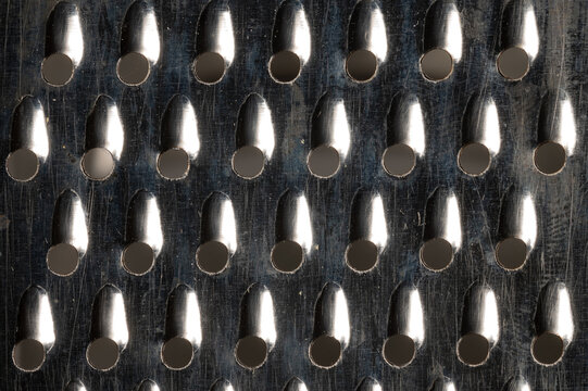 Close-up pattern of the holes of an old kitchen grater with rust elements. Grunge background