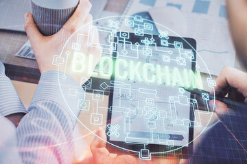 Double exposure of man's hands holding and using a phone and crypto currency blockchain theme...