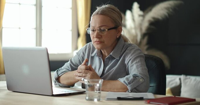 Mature woman reads negative results about work. Loss of network work. Anxious closing the laptop. Emotional tiredness. Closing her laptop after reading a dismissal notice.