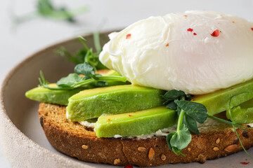 Sandwich with avocado, poached egg, sprouts and soft cheese for healthy breakfast on white background. close up