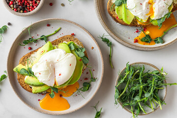 Sandwiches with avocado, poached egg, sprouts and cheese for healthy breakfast on white background. top view