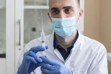 The doctor is holding a syringe. An injection of the coronavirus vaccine in hands of a medical worker in a hospital.