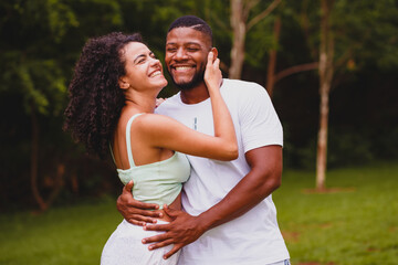 Afro Brazilian couple, holding hands holding each other exchanging caresses and kisses, smiling,...